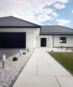 a white house with black garage doors on the front and side walk leading to it