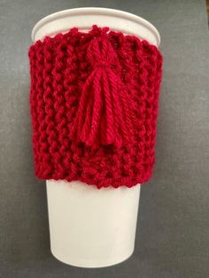 a red knitted cup cozying on top of a coffee cup