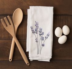 a wooden spoon, fork and two eggs on a table next to some napkins