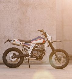 a dirt bike parked in front of a building with the sun shining down on it