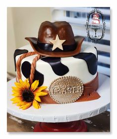 a cake decorated with a cowboy hat, sunflowers and a star on top