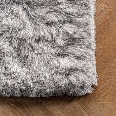 a close up view of a rug on a wooden floor with grey and white fur