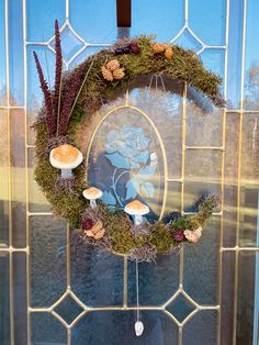 a wreath with mushrooms and moss hanging on the front door to decorate it's entrance