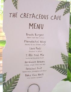 a menu for the cretaceous cafe is displayed on a white board with green leaves