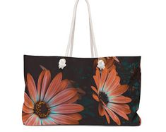 an orange and blue flower on black background with white handles is shown in this large tote bag