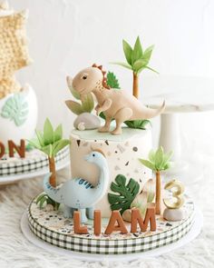 there is a cake decorated with dinosaurs on the top and letters that spell out i am