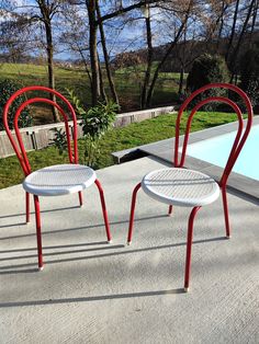 two red and white chairs sitting next to a swimming pool