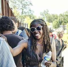 a woman with dreadlocks and sunglasses standing next to other people