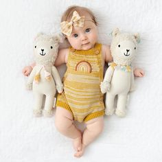 a baby is laying on the floor with three stuffed animals in front of her and looking at the camera