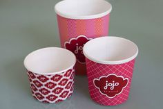 three pink and red paper cups sitting next to each other on top of a table