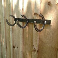 two metal hooks are attached to a wooden fence