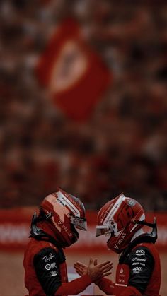 two football players sitting on the sidelines with their hands together