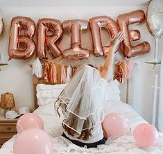 the bride is sitting on her bed surrounded by balloons