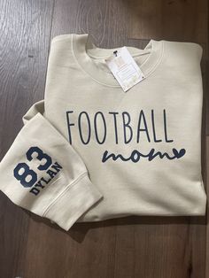 This crew neck sweatshirt makes the perfect gift for football moms. Choose  your size and shirt color from the drop menu below. Make sure to fill out the personalization section with your child's jersey number and name and your choice of font color. This will be added to the sleeve of the shirt. Font colors are navy, black, white, red, gold, bright yellow, forest green, or orange. Email us for a specific color shade.   Adult Unisex  50/50 Fleece Crew Football Mom Sweater, Football Sweatshirts Vinyl, Names On Sleeves Of Shirts, Diy Football Mom Shirts, Football Mom Shirts Ideas Design, Cricut Sports Shirt Ideas, Sports Mom Shirts Ideas, Football Mom Sweatshirt Ideas, Football Mom Shirts Ideas Sons