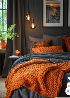 a bed with orange blankets and pillows in a bedroom next to two pictures on the wall