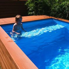 a young boy is playing in the pool with his feet on the edge of the water