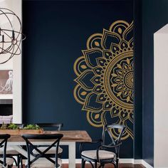 a dining room table with chairs and a wall painted in blue, gold and white