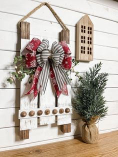 a wooden sign with a bow hanging from it's side next to a potted plant