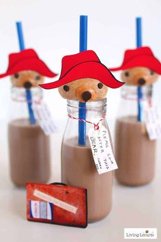 there are three small bottles with chocolate milk and straws in them, one has a red hat on top