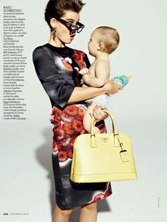 a woman holding a baby in her arms while standing next to a yellow handbag