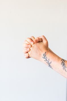 a person's arm with tattoos on it and one hand holding something in the air