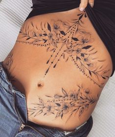 a woman's stomach with tattoos on it and her hand resting on the belly