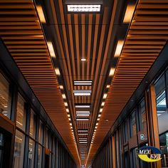 an empty hallway is lit up with lights and wood slats on the ceiling above