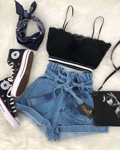 a pair of high waisted shorts and converse sneakers are laid out on a white furnishing