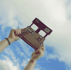 two hands are holding up a piece of cardboard that looks like a floppy disk drive