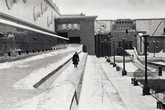 black and white photograph of a person walking down the street in winter with snow on the ground