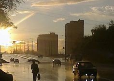 people walking in the rain with umbrellas on a city street at sunset or dawn