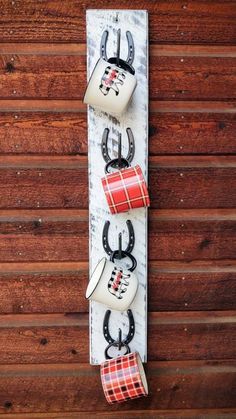 three mugs are hanging on the wall with black and white plaid ribbon attached to them