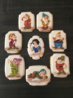 seven decorated cookies sitting on top of a wooden table