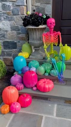 colorful halloween decorations on the steps in front of a house with a skeleton statue and pumpkins