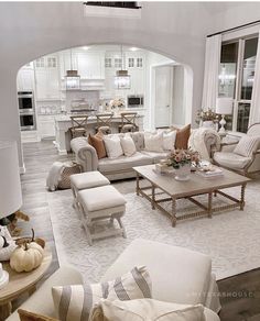 a living room filled with white furniture and lots of pillows on top of it's couches