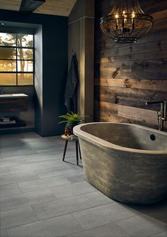 a large bath tub sitting in a bathroom next to a wooden wall with lights on it