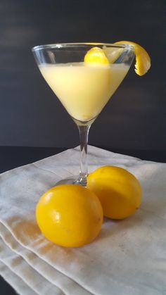 two lemons sit on a napkin next to a martini glass filled with yellow liquid