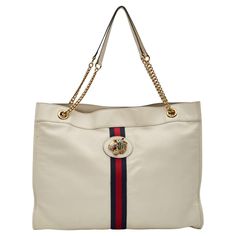 This Gucci tote by Alessandro Michele is constructed of neutrals leather, featuring the signature Sylvie Web accent and Rajah detail. The bag showcases gold-tone hardware, chain-link shoulder straps, crystal tiger head and chain-link accents. The bag is secured with a snap closure at the top and is finished with suede lining with an interior pocket. Vintage Authenticated by entrupy. Color: White with web Material: leather Model No. 537219 Condition: Very good. Faint hairline marks. Bag was refurbished by leather professional. Made in Italy Measurements~ Height 13.75” Width 17.25” Depth 1.75” Drop 10.25” Gucci Tote, Tiger Head, Alessandro Michele, Fashion Handbags, White Leather, Chain Link, Gucci, Tote Bag, Purses And Bags