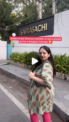 a pregnant woman standing in front of a sign that says sayyasachi on it