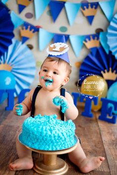 a baby sitting in front of a cake with blue frosting