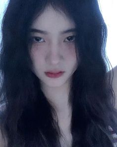 a woman with long black hair is looking at the camera