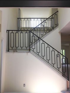 a stair case in an empty room with white walls and black iron balconies