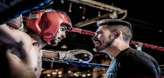 two men standing next to each other in a boxing ring wearing red and black gloves