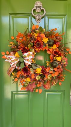 a green front door with a wreath on it and an orange flower arrangement in the center