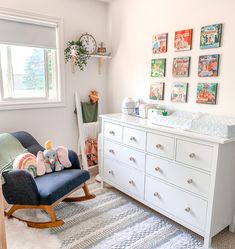 a baby's room with white furniture and pictures on the wall