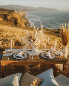 an outdoor table set with place settings for two, overlooking the ocean and cliffs in the distance