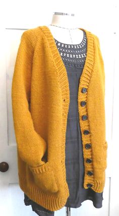 a yellow cardigan sweater hanging on a white door