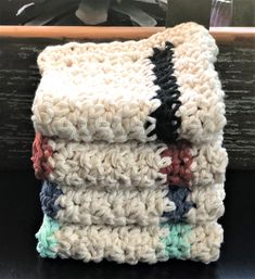 three crocheted dishcloths stacked on top of each other in front of a plant