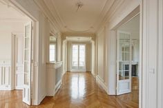 an empty hallway with wooden floors and white walls