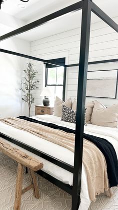 a bedroom with a four poster bed and white walls